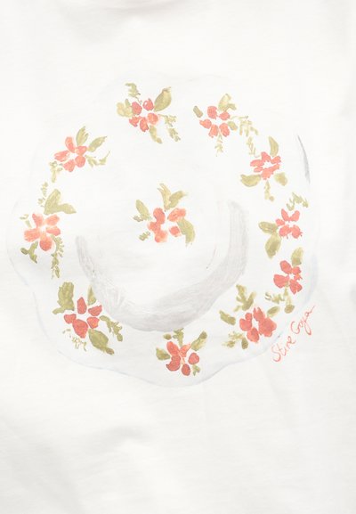 Λευκό καπέλο με πλατιά γείσο και κυματοειδείς άκρες, διακοσμημένο με ροζ και πράσινα ανθικά μοτίβα και μια μικρή υπογραφή σε πορτοκαλί.