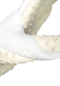 Gant en textile blanc avec une prise texturée, comportant des nodules ronds en relief et une zone de poignet lisse et à motifs. Marque visible en gris clair.