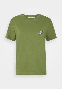 Vihreä lyhythihainen crew neck -t-paita, jossa on pieni sininen ja keltainen brodeerattu lintu vasemmassa rinnassa.