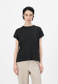 Svart t-shirt med kort ärm, tillverkad av mjuk bomull. Har en avslappnad passform med uppvikta ärmar och rund halsringning. Enkla, ensfärgade design.