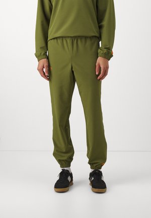 Olive green sweatpants with elastic waistband and cuffs. Features an orange accent detail near the cuff. Made from soft, stretchy fabric.