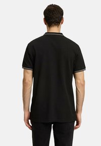 Czarna koszulka polo o solidnym wzorze, krótki rękaw i kontrastowe paski na kołnierzyku oraz mankietach.