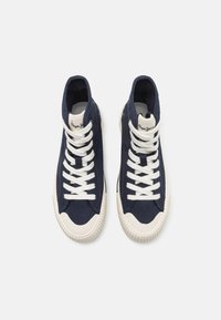 High-top sneakers in navy canvas, featuring white laces and a cream rubber sole. Textured fabric with logo detail on the tongue.