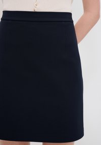 Marineblauer Bleistiftrock aus einem glatten, strukturierten Stoff, mit einem hohen Taillendesign und ohne sichtbare Taschen. Einfache, klare Linien.