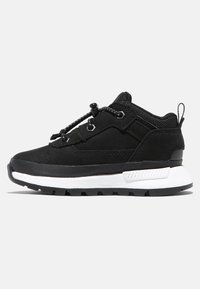 Zapatilla deportiva negra con parte superior de ante y tejido, acentos texturizados en negro y una media suela blanca. Presenta cordones elásticos y una suela resistente.