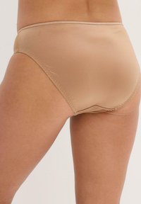 Mutande beige a vita alta realizzate in tessuto morbido, con cuciture pulite e un design senza soluzione di continuità per il massimo comfort.