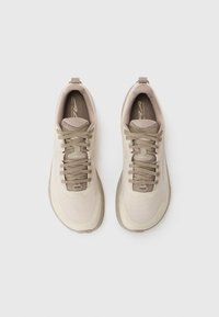 Chaussures de trail beiges et marron clair avec des lacets, vues de dessus sur un fond blanc uni.