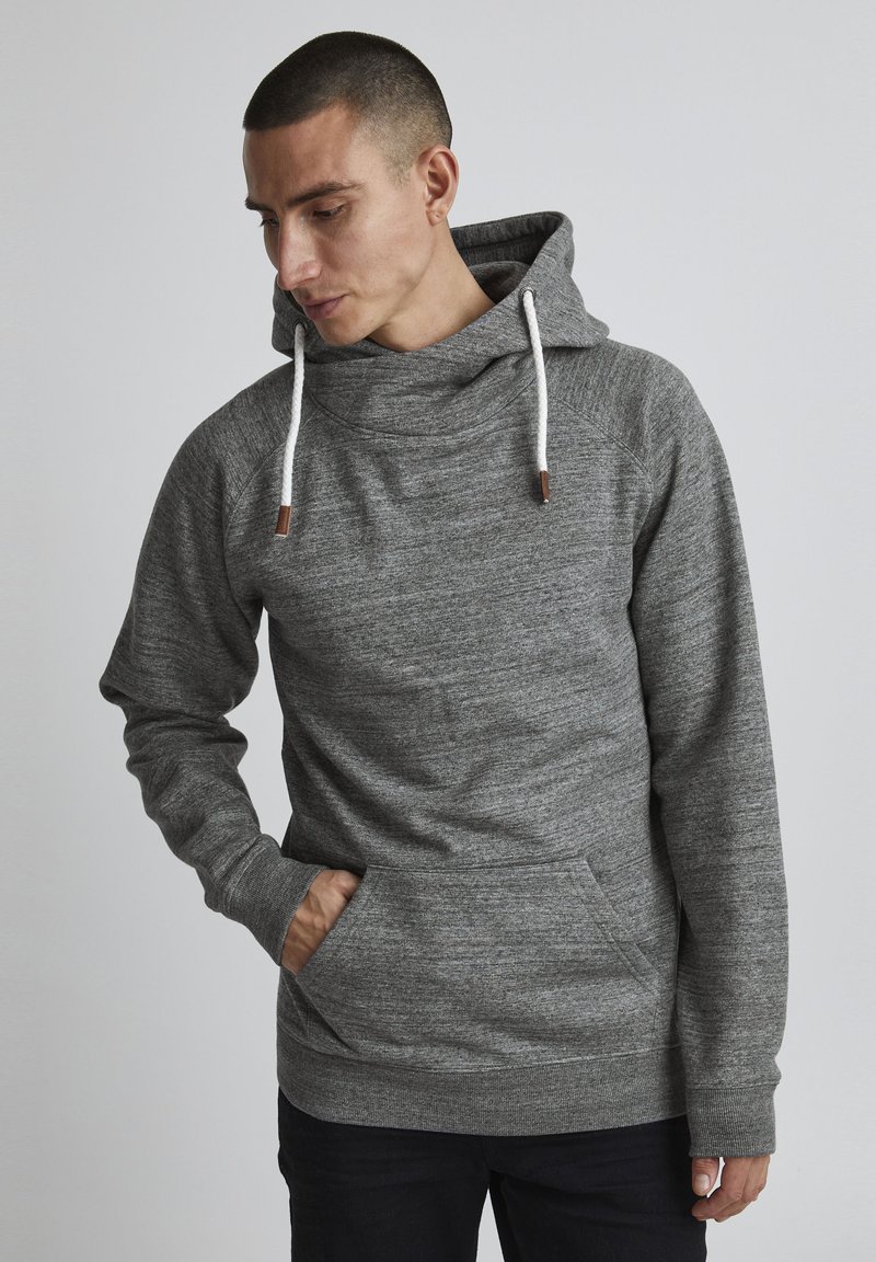 Sudadera gris con cuello tipo embudo, cierre con cordón y bolsillo canguro. La tela parece suave y texturizada, con puños y dobladillo acanalados.
