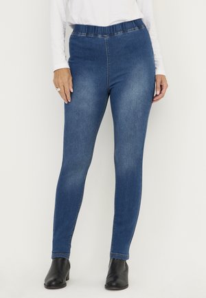 Blå denimleggings med elastisk midja, slim fit och lätt blekning. Bärs med svarta ankelskors som har en slät yta och inga synliga fickor.