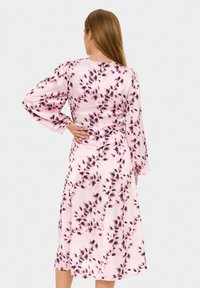 Rosenblumenkleid mit langen, gepufften Ärmeln und taillierter Passform. Der Stoff weist ein Aquarellmuster in dunkleren Rosa- und Schwarztönen auf.