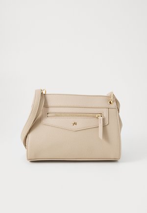 Sac bandoulière beige texturé avec fermeture éclair dorée et petit logo doré sur la poche avant, doté d'une bandoulière réglable.