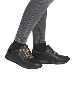Des baskets en cuir noir présentent une finition texturée, des lacets marron, une fermeture éclair sur le côté et une semelle en caoutchouc à profil bas avec une ligne d'accent dorée.