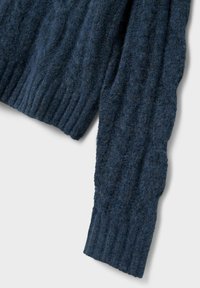 Ciemnoniebieski sweter o teksturowanej fakturze z prążkowanym dołem i mankietami, zdobiony wzorem tkanym. Materiał wydaje się ciepły i gruby.