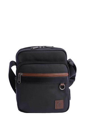 Bolsa bandolera negra de lona con un acento de cremallera marrón, cierre de doble cremallera, correa ajustable y un pequeño parche de logo en la parte frontal.