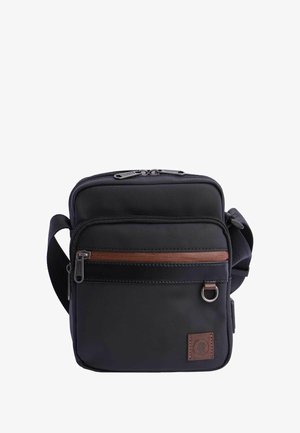 Bolsa bandolera negra de lona con un acento de cremallera marrón, cierre de doble cremallera, correa ajustable y un pequeño parche de logo en la parte frontal.