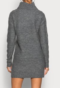 Robe pull grise en tricot avec un col montant, des manches longues et un ourlet côtelé, présentant un tissu texturé et une coupe décontractée.