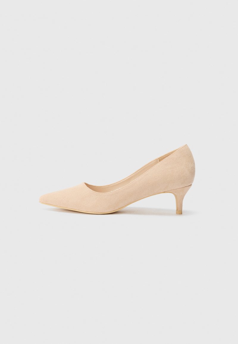 Zapato de tacón alto de ante beige con punta afilada y tacón delgado de 5 centímetros. Textura suave con un detalle mínimo en la superficie superior.