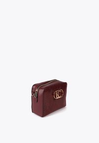 Borsa cosmetica compatta in bordeaux con logo dorato e design testurizzato, dotata di chiusura a zip superiore e forma rettangolare.