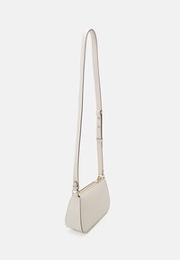 Light beige leather handbag with a rounded bottom, thin shoulder strap, and gold-tone hardware. Features clean lines and minimalistic design.