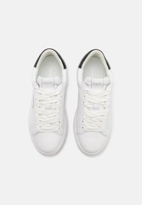 Zapatillas de cuero blanco con textura suave, punta redonda y cordones blancos planos. Acentos negros en el talón realzan el diseño.