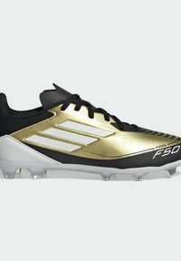 Botín de fútbol negro y dorado con parte superior texturizada, detalles en blanco y una marca prominente. Presenta un diseño elegante con tacos moldeados.