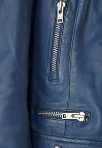 Modrá kožená bunda s hladkým povrchem, několika stříbrnými zipy a strukturovaným designem s panelovými detaily.