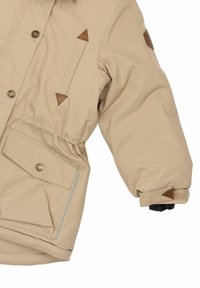 Beige Winterjacke mit einem Kapuzenrand aus Fell, elastischer Taille, großer Fronttasche und braunen Lederakzenten an Schultern und Manschetten.