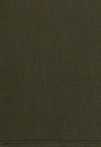 Tissu vert olive foncé avec une texture fine en tricot et une couture horizontale visible au bord inférieur.
