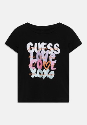 Schwarzes kurzärmeliges T-Shirt mit buntem fettem Schriftzug „GUESS LOVE COOL XOXO“ und kleinen orangefarbenen kursiven Wörtern sowie einem Herz in der Mitte.