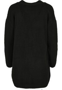 Pull en tricot noir avec une coupe décontractée, des épaules baissées et un col rond. La texture est douce, avec des poignets et un ourlet côtelés.