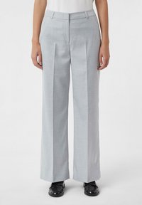 Lichtgrijze, wijdvallende broek met een gladde textuur en twee voorplooien. Heeft een standaard tailleband en zijzakken.