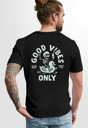 Schwarzes Kurzarm-T-Shirt mit einem Grafikdruck eines Skeletts auf einer Ente, dem Text "NUR GUTE VIBES" und den Phrasen "OCEAN DRIVE" und "BEACH CLUB."