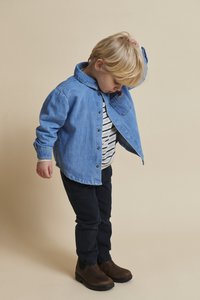 Blå denim skjorte med knapper, stripete skjorte under, mørke bukser og brune ankelstøvler; barn står med hodet ned, ser på fottøyet.