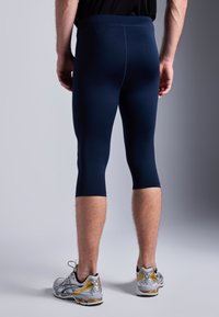Tengerészkék sport leggings, amely szoros, sima illeszkedéssel rendelkezik, és a vádli közepéig ér. Széles derékpánttal és minimális varrási részletekkel rendelkezik.