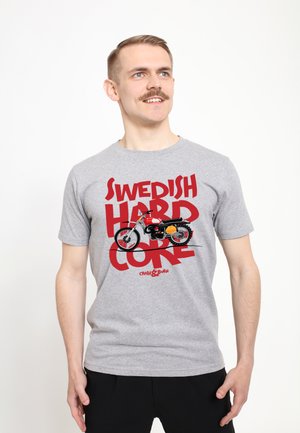 Camiseta de algodón gris con un texto rojo en negrita que dice "SWEDISH HARD CORE" y un gráfico de una motocicleta, con mangas cortas y un escote redondo.