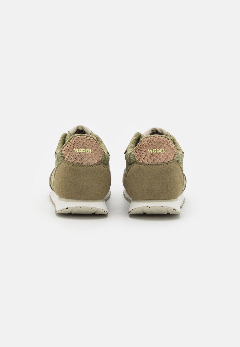 Grüne Wildleder- und Mesh-Sneaker mit einer strukturierten braunen Ferse und goldener Aufschrift "WODEN", ausgestattet mit einer weiß gesprenkelten Sohle.