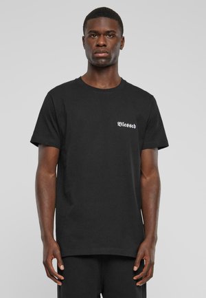 Sort bomulds T-shirt med rund hals og korte ærmer, med hvid "Blessed" tekst på venstre bryst. Glat overflade, afslappet pasform.