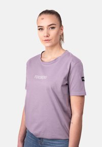 Camiseta de manga corta de color lavanda hecha de algodón suave, con el texto "FORSBERG" en blanco en el pecho y una pequeña etiqueta negra en la manga.