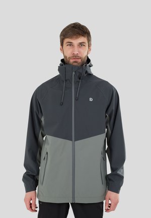 Man die naar voren kijkt, draagt een tweekleurige grijze capuchonjas met ritssluiting en ritssluitingszakken tegen een effen lichtgrijze achtergrond.