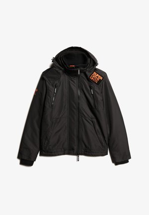 Czarna kurtka z kapturem, wykonana z gładkiej tkaniny syntetycznej. Posiada zamykane na zamek kieszenie i pomarańczowe logo na górnej lewej stronie.