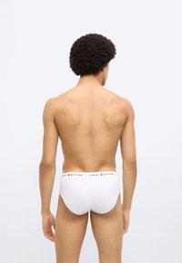 Λευκά βαμβακερά εσώρουχα με λογότυπο στη μέση, προβολή από πίσω. Κοντή κοπή, ομαλή υφή, μίνιμαλ σχεδίαση, χωρίς επιπλέον σχέδια.