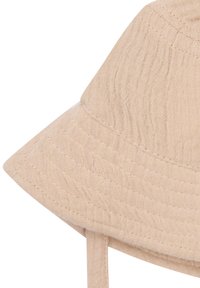 Beiger Bucket Hat aus strukturiertem Stoff, mit breiter Krempe und gebundenen Trägern für einen sicheren Sitz. Sichtbare Nahtdetails verbessern das Design.