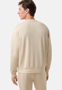 Beige mikina s kulatým výstřihem, žebrovanými manžetami a pasem. Měkká textura, volný střih a čistý design bez log a vzorů.