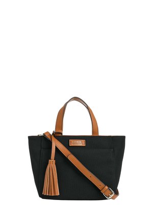 Sac fourre-tout noir avec poignées en cuir marron, bandoulière ajustable, pompon assorti et petite étiquette de marque sur la poche avant.
