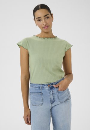 Light green ribbed top with a scalloped neckline and cap sleeves. Paired with high-waisted blue denim jeans featuring pockets.