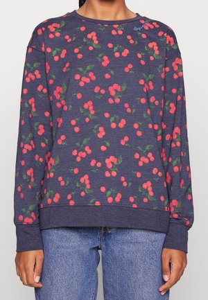 Mørkeblå langærmet sweatshirt med røde kirsemønstre og grønne blade, båret med blå denimjeans.