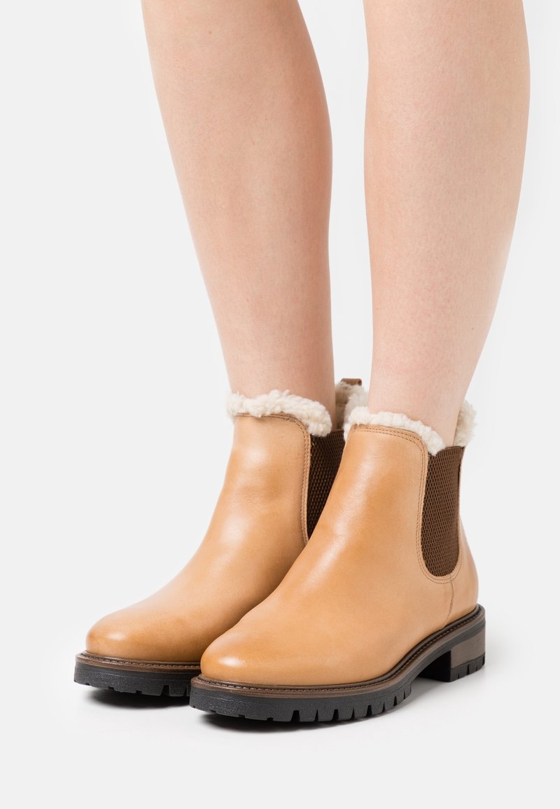 Bottes à cheville en cuir fauve avec une finition lisse, doublure en peau de mouton, panneaux élastiques latéraux et semelle en caoutchouc texturée pour une meilleure adhérence.