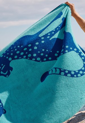 Serviette turquoise avec des motifs d'animaux et des taches bleu foncé, dotée d'une surface douce et texturée et d'un design vibrant et contrasté.