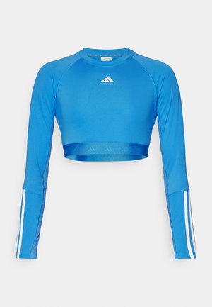 Blue long-sleeve cropped sports top made of a smooth material featuring white stripe accents on sleeves and a small logo on the chest.