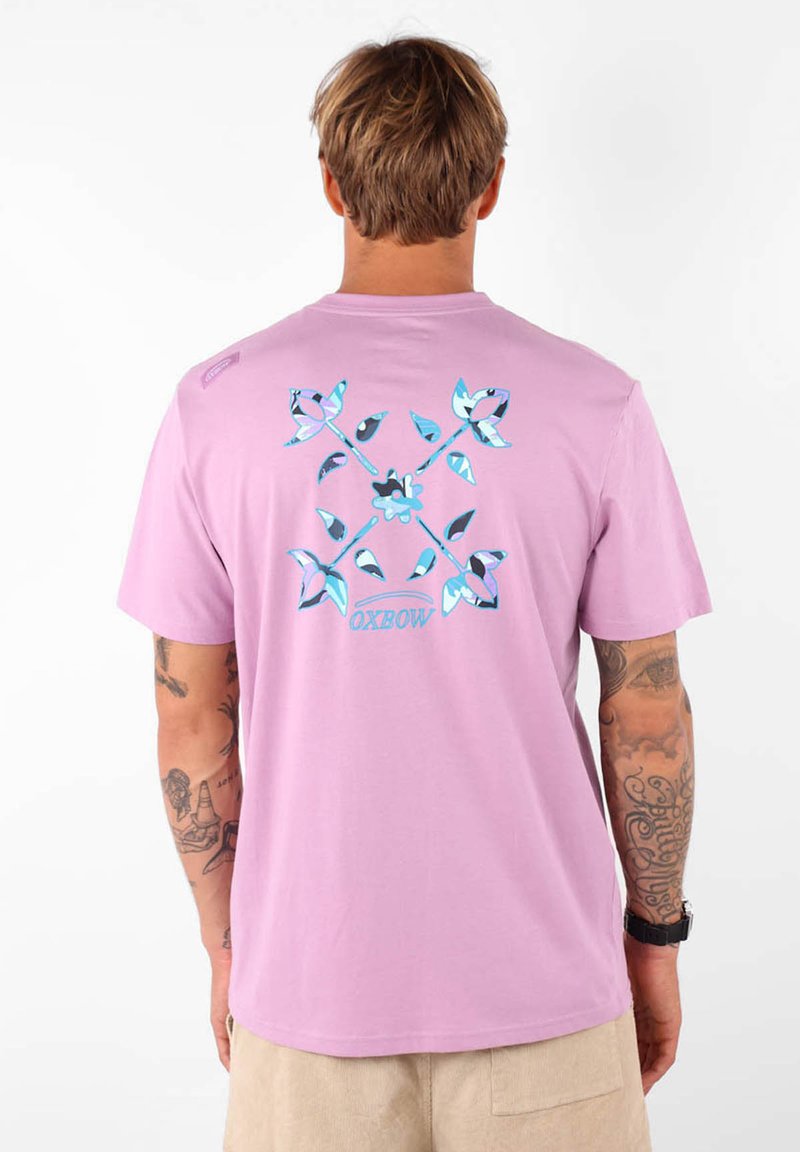 T-shirt rose clair en coton avec un design graphique comportant des accents et des formes bleues au dos ; manches courtes et coupe décontractée.